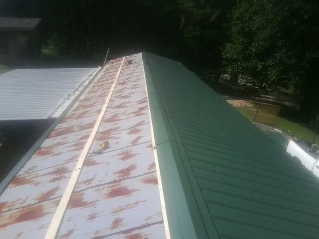 Old rusted panels beside newly installed green metal roofing — Wind Damage Roof Repair by Roofing Brothers in Mont Alto
