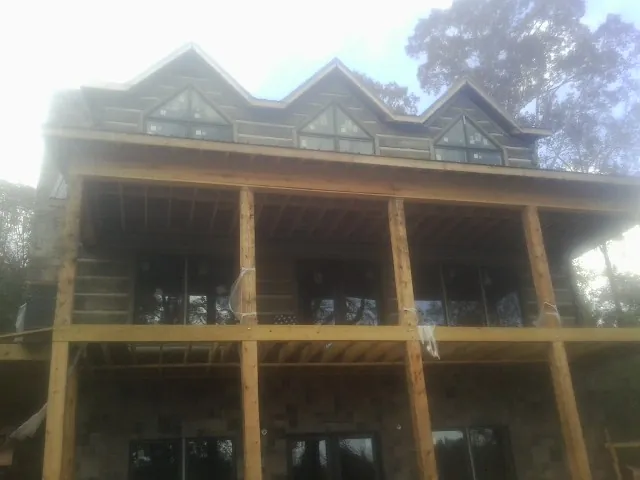 Dormers and porch framing on a large log home under construction — Roof Coating work by our crew in Mont Alto
