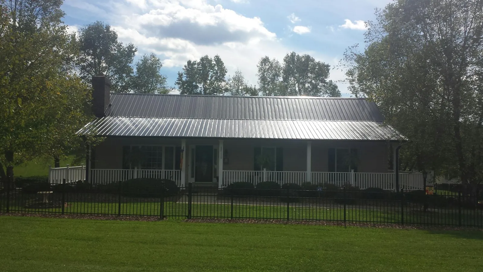 Gray metal roof on a brick ranch with a full width front porch — Gutter Guard Installation work by our crew in Mont Alto