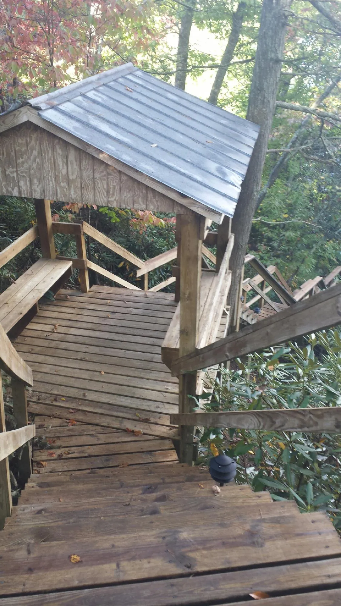 Metal roofed shelter over wooden steps on a wooded walkway — Skylight Repair & Installation work by our crew in Mont Alto
