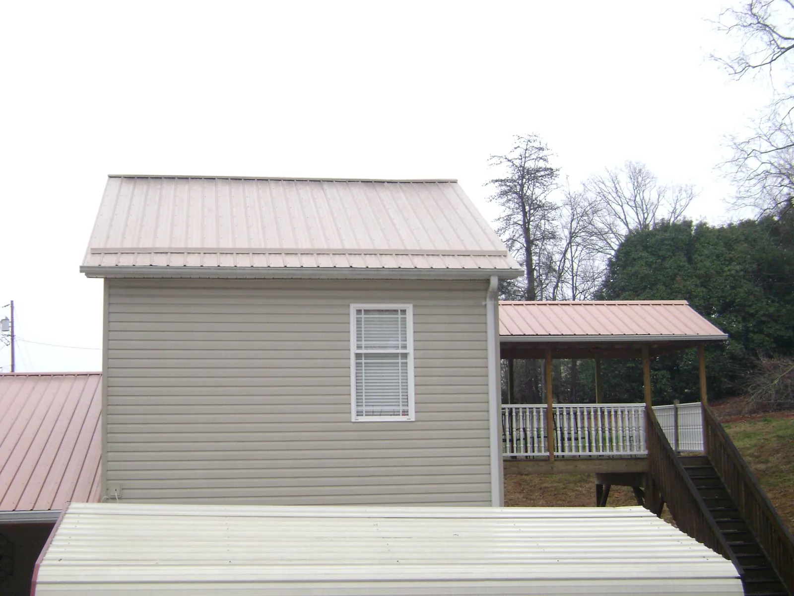 Tan metal roofs on a two story addition and attached porch, from a Roof Replacement job in Mont Alto