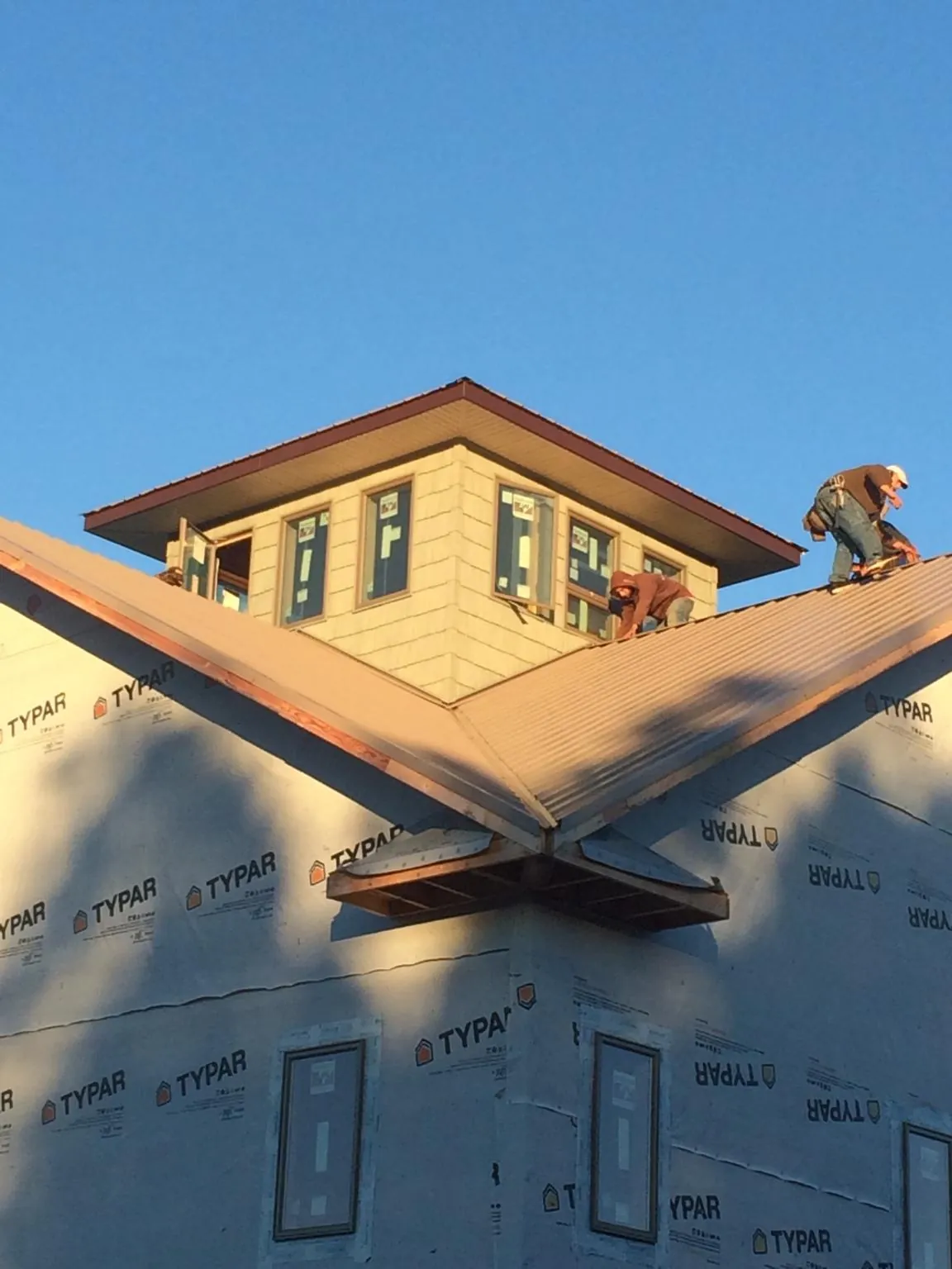 Roofers working around a rooftop cupola on a new metal roof at sunset — Roof Waterproofing in Mont Alto by Roofing Brothers